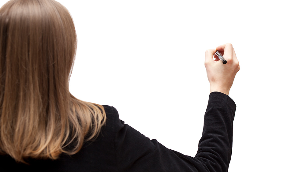 Woman writing on whiteboard.