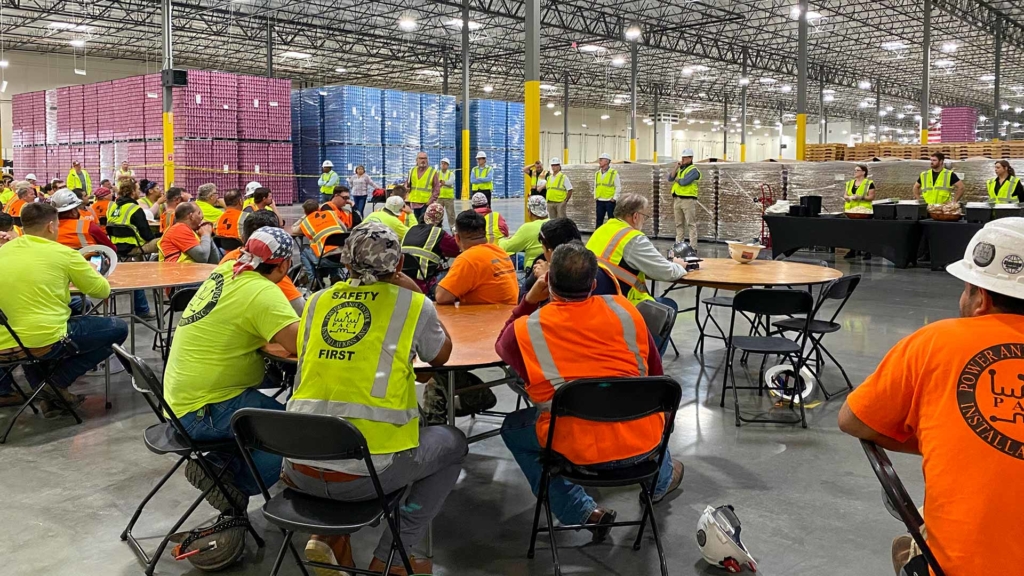 A Haskell construction crew gathers for a meeting in Bang Energy's giant warehouse