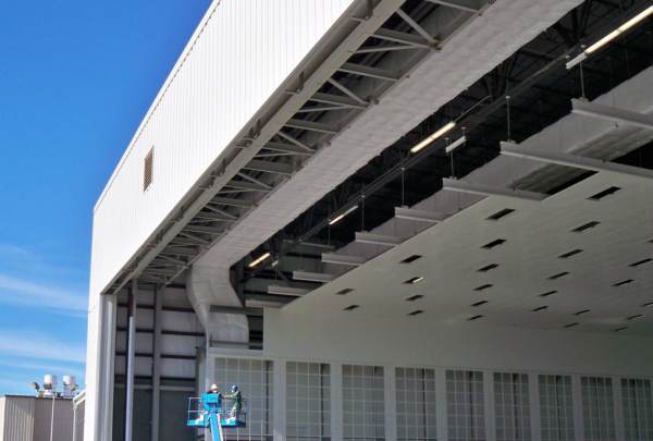 Exterior of Gulfstream Paint Hangar. Large white building and blue sky.