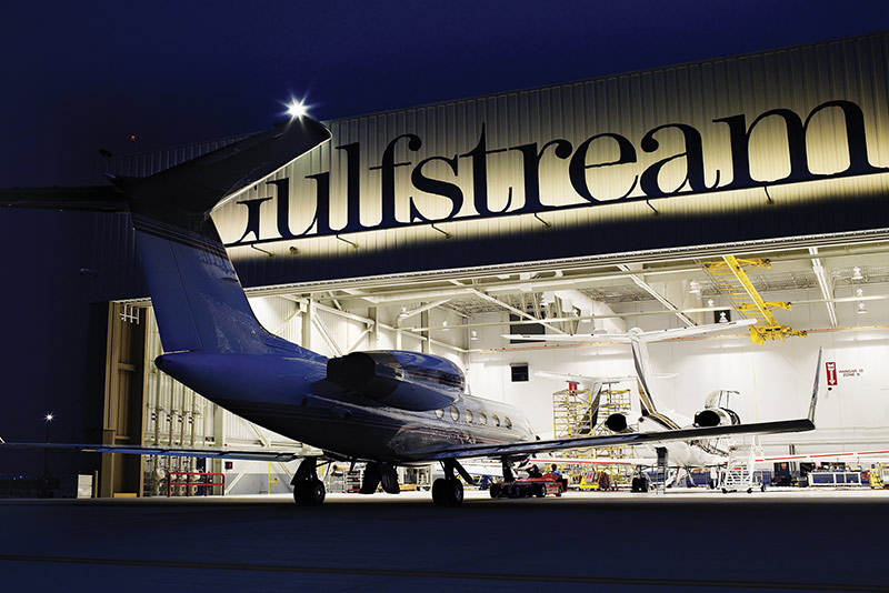 Exterior of Gulf Stream Service Center at night. Plane entering hangar.