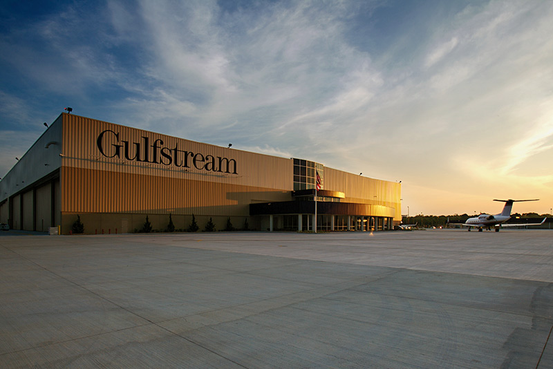 Exterior of Gulfstream Service Center at dusk. Airplane sitting outside of large rectangular building.