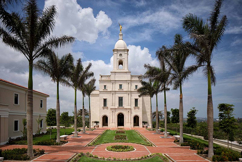 Exterior photo of the Latter-Day Saints temple. Palm trees line the landscaped brick walkways leading to the entrance.