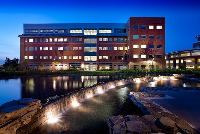 Exterior photo of the Northwest Specialty Center at night. A pond and rock waterfall are in the foreground..