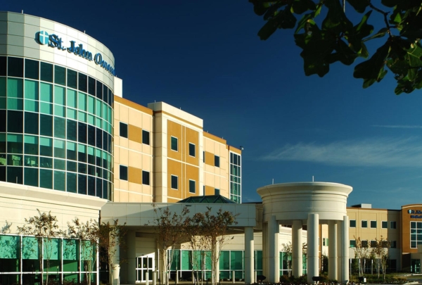 Exterior photo of Owasso Hospital and Medical Office Building. Four-story hospital entrance against bright blue skies.