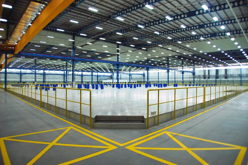 Interior of Spirit AeroSystems SE Asia. Large industrial open room with yellow railing and florescent lighting.