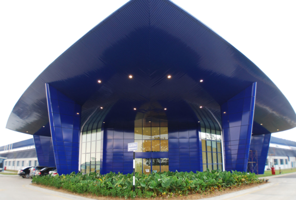 Exterior entrance of Spirit AeroSystems SE Asia. Bright blue airfoil inspired triangular building.