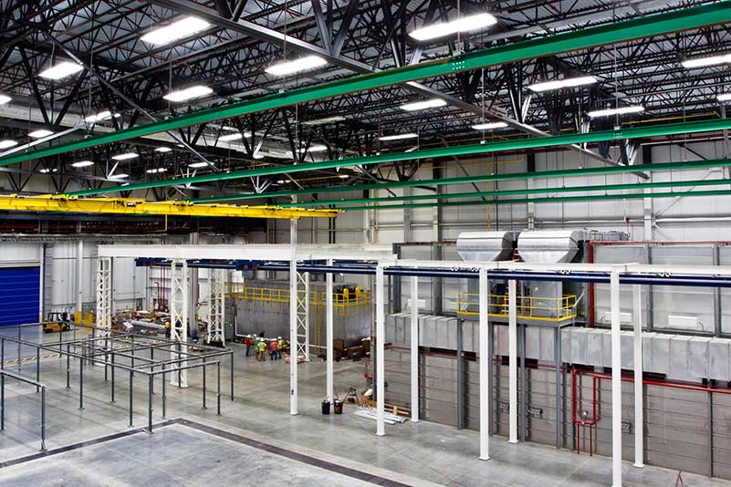 Interior of Spirit AeroSystems Composite Center. Large industrial room with green, yellow and white rafters.