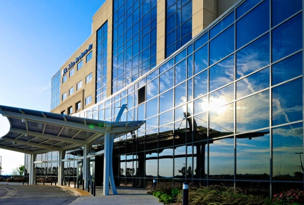 Exterior photo of St. Johns Broken Arrow Medical Campus. Sun reflecting off the six-story glass building.