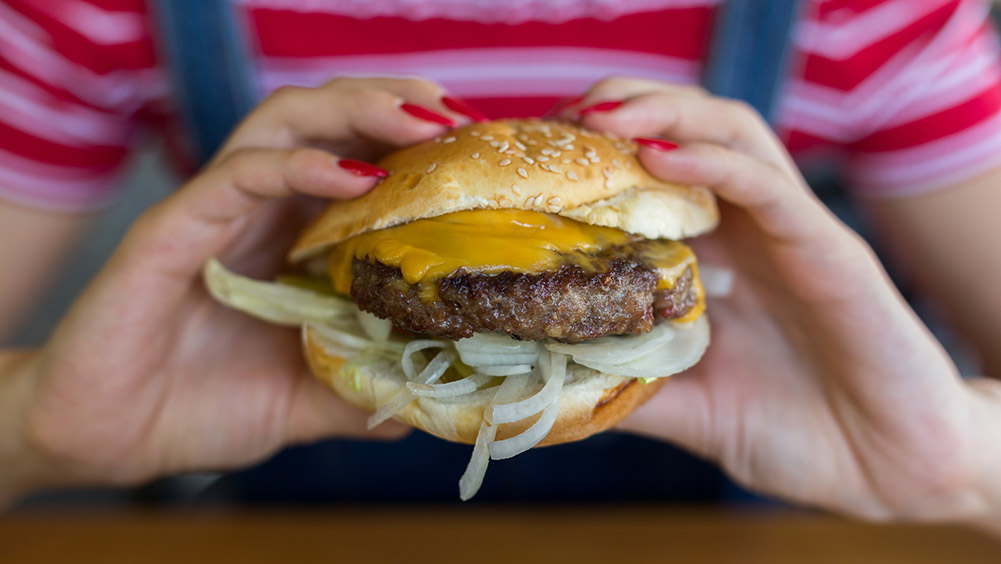 Woman eating a cheeseburger.