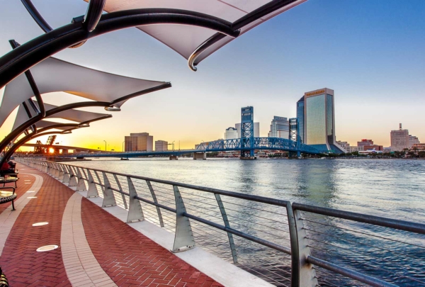 Walkway next to the river with city skyline in the background.