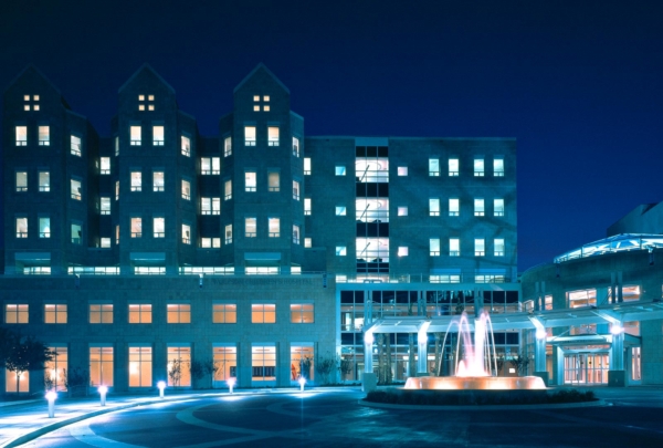 Exterior photo of Wolfson Children's Hospital at night. Blue lights and fountain surrounded by brick circle drive.