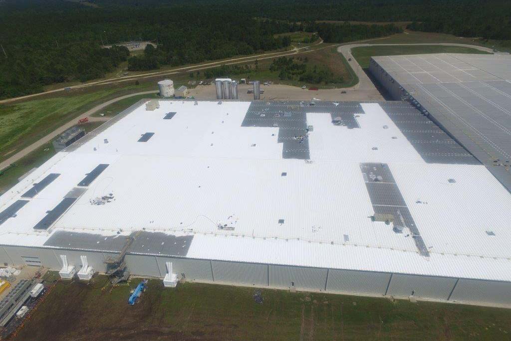 To enable a quick return to production, roofers applied a spray coating to create a temporary watertight seal. White rooftop areas in the picture indicate sections that received coating.