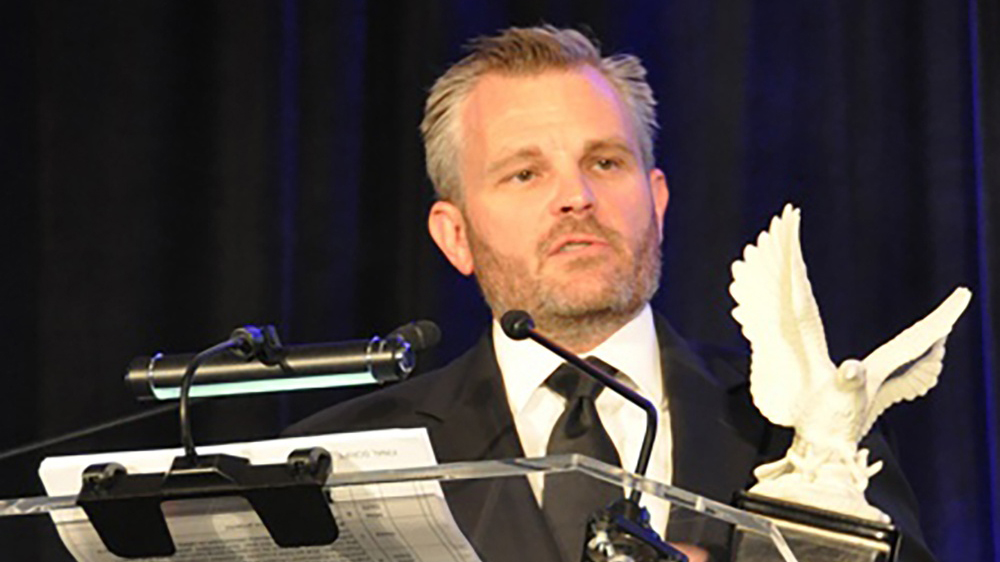 Bryan Bedell speaking at a podium.|