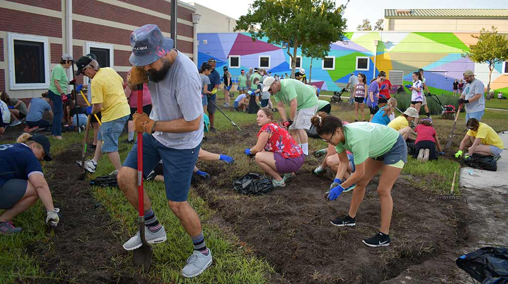 Haskell team members landscaping the front of a middle school.|Haskell team members landscaping.||