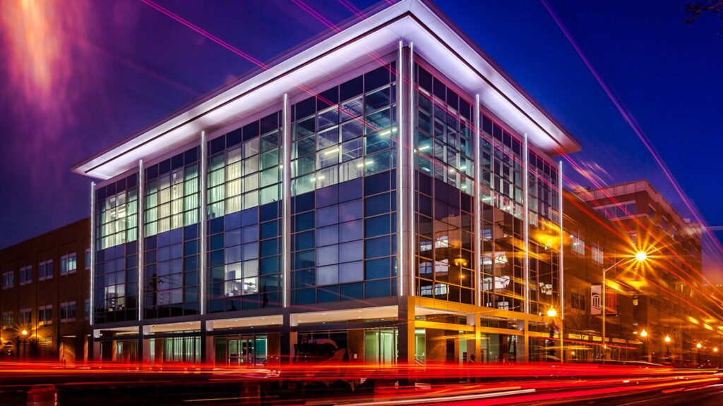 Exterior photo of Maryland Proton Treatment Center at night. Vehicle taillights create red streaks in time lapse image.