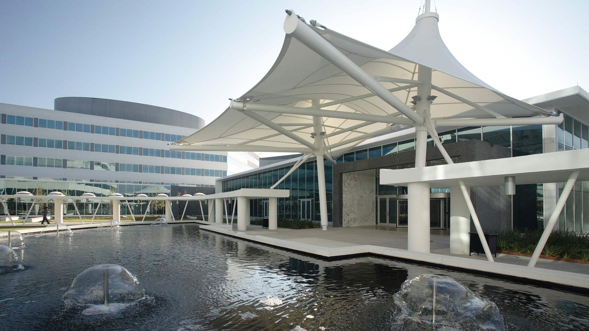 Pool and fountains on Blue Cross Campus|Dining Room with high ceiling and glass walls on all sides|Exterior photo of Cafeteria and Office Building reflecting in retention pond|Aerial view of Blue Cross & Blue Shield Campus|Parking Facility|Dark blue background image||||||
