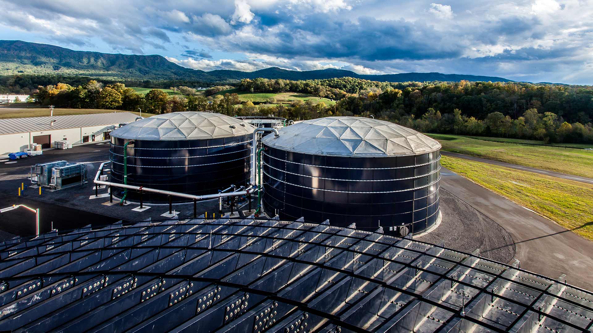 Exterior photo of 2.5 mgd process water reclamation facility|Water testing lab|Large Delta Blowers inside the facility with other controls and machinery in the background|Clarifier tank and process piping|Green pipes outside the facility|Exterior photo of tanks and vertical processing equipment|Stainless steel water testing lab and control room|Piping