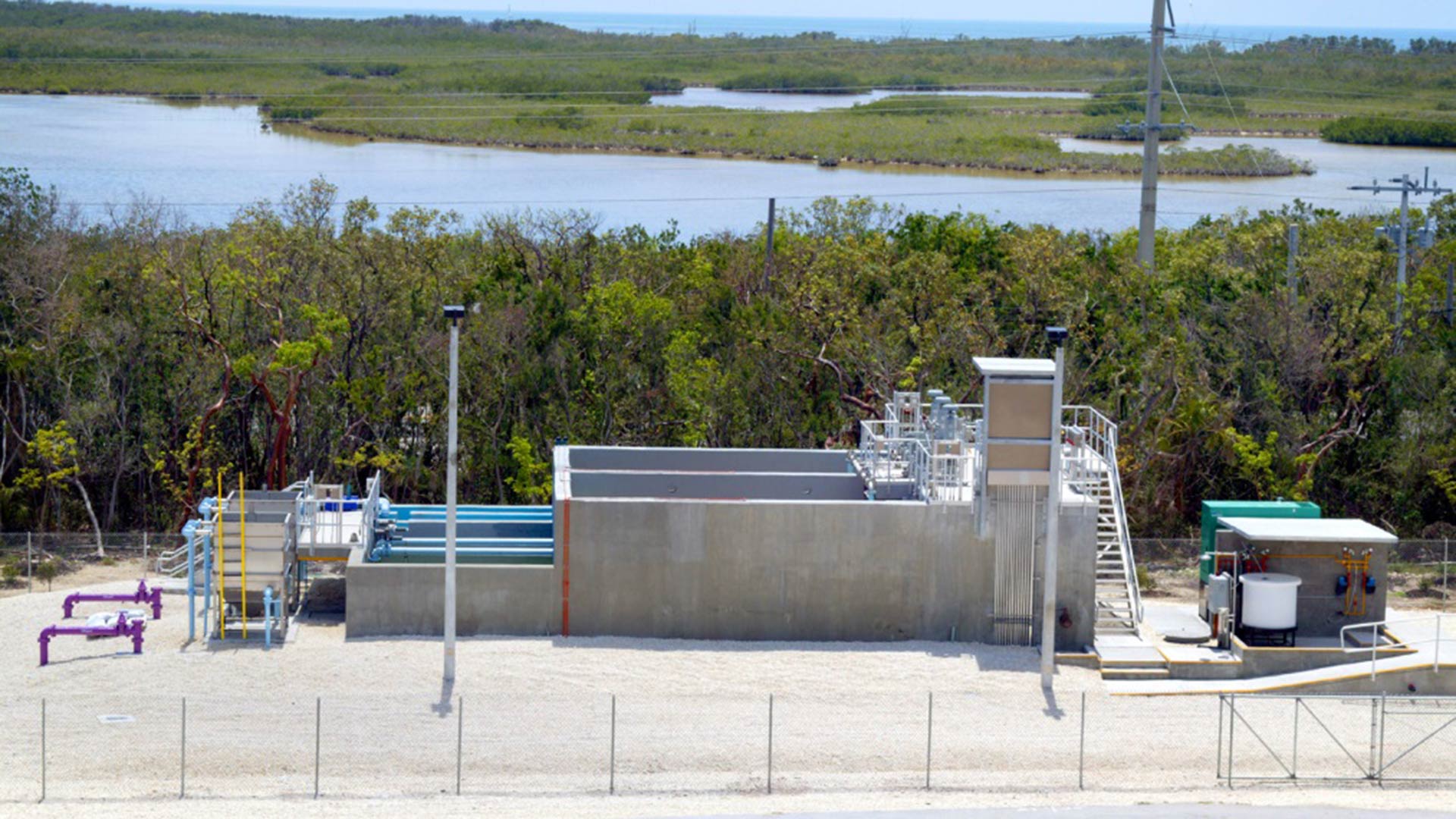 Looking down at the Layton wastewater treatment system. Purple and blue pipes extend out of the ground and system.|Looking down at the Layton wastewater treatment system. Purple and blue pipes extend out of the ground and system.|Pipes