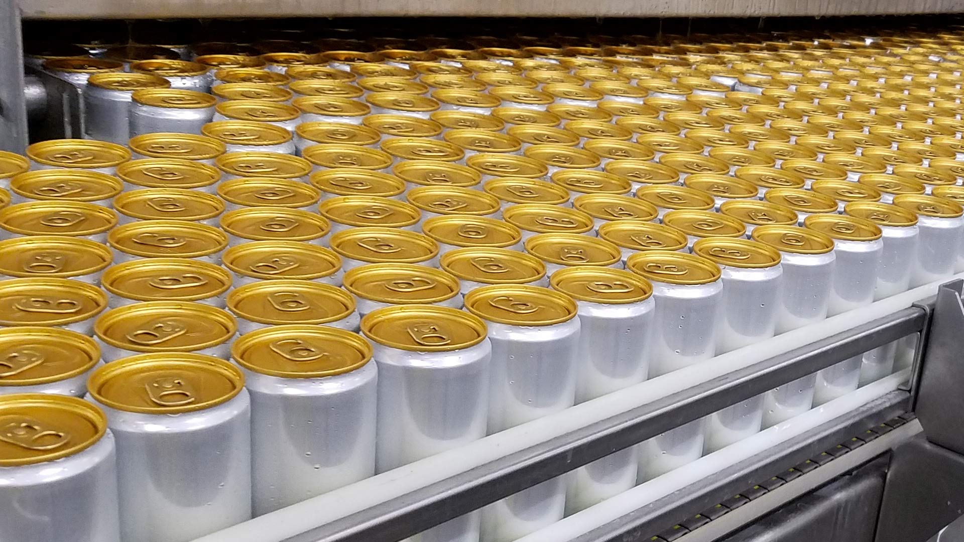 Filled seltzer cans await labeling|Filled seltzer cans await labeling|Interior of Lidestri seltzer facility|Overhead and spiral conveyor system|Filled seltzer cans on conveyor|Filled seltzer cans await sleeving|Filled seltzer cans await labeling|||||||