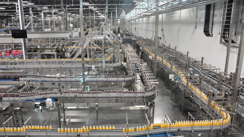 Automated beverage bottling and conveyor system operating in a large-scale food and beverage manufacturing facility.