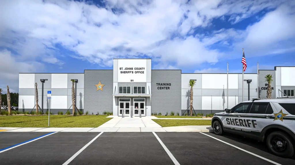 Front entrance of the St. Johns County Sheriff’s Office Training Center with an American flag and sheriff vehicle.