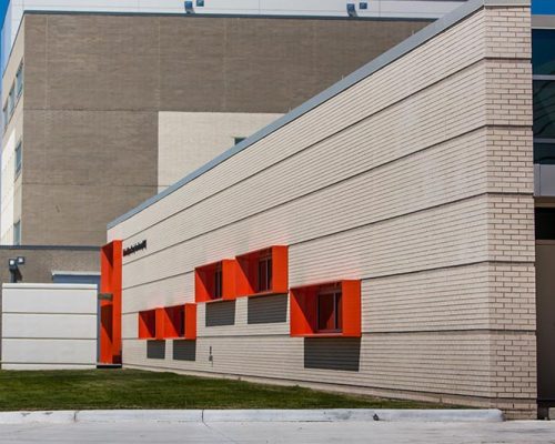 Building exterior featuring bright red metal panel window cowlings
