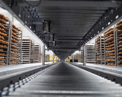 Quik Trip conveyor system flanked by portable racks filled with baked goods