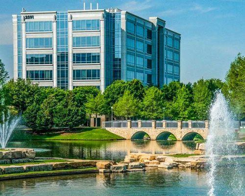 Exterior photo of Dallas office building with fountain and bridge