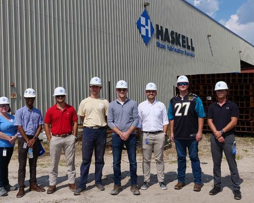 Group wearing Haskell hardhats gather outside Haskell Steel facility.