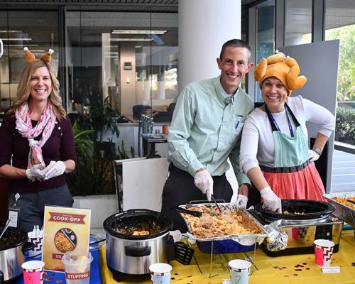 A few volunteers serve cook-off meals while wearing silly hats.