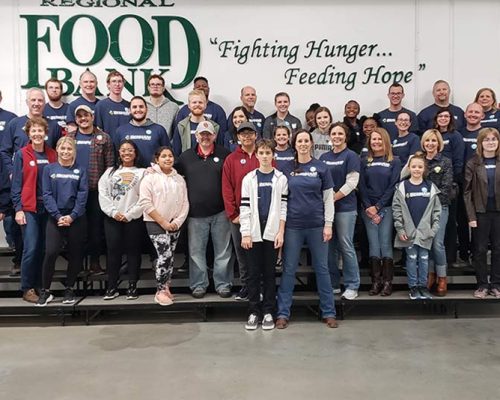 A large group of Benham team members gather for a photo as they volunteer at the Regional Food Bank of Oklahoma
