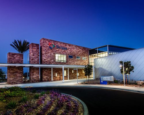 Exterior photo of California Proton Cancer Therapy Center at dusk of entrance drive and landscaping.