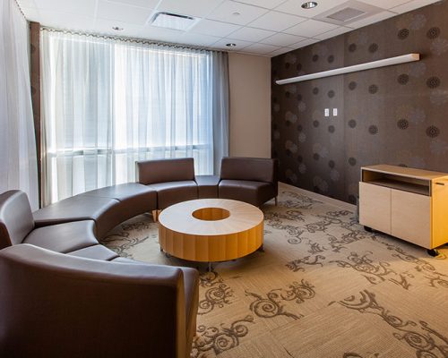 Photo of seating at the California Proton Cancer Therapy Center. Round brown leather couch around doughnut shaped table.