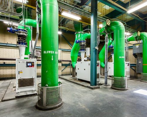 Large green pipes inside the facility and other controls/equipment.