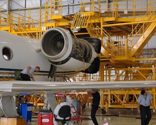 Men working on airplane inside the Gulfstream International Service Facility.