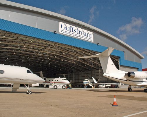 Exterior of Gulfstream International Service Facility with planes within the hangar.