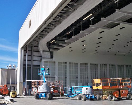 Exterior of Gulfstream Paint Hangar under construction. Large white building and blue sky.