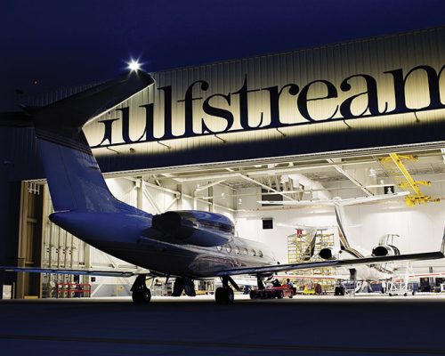 Exterior of Gulf Stream Service Center at night. Plane entering hangar.