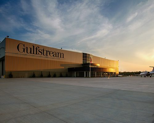 Exterior of Gulfstream Service Center at dusk. Airplane sitting outside of large rectangular building.