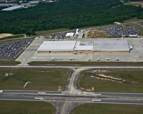 Aerial view of Gulfstream Service Center. Rectangular building surrounded by parking lots and parked aircraft.
