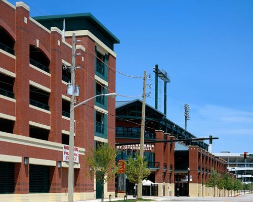 Exterior photo of Jacksonville Municipal Garages. Photo is a street view of the arena and sports parking garage. Red brick with green trim and accents.