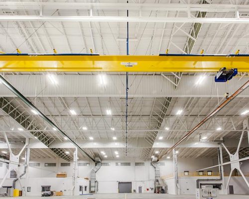 Interior of Lufthansa Technik Heavy Maintenance Facility. Large open space with white walls, bright lighting and yellow ceiling beams.