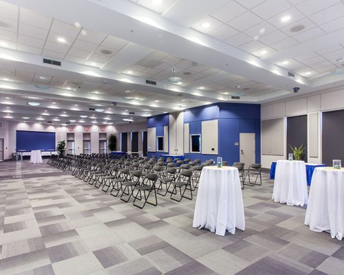 Interior photo of a large room with chairs and bar height tables ready for a presentation.