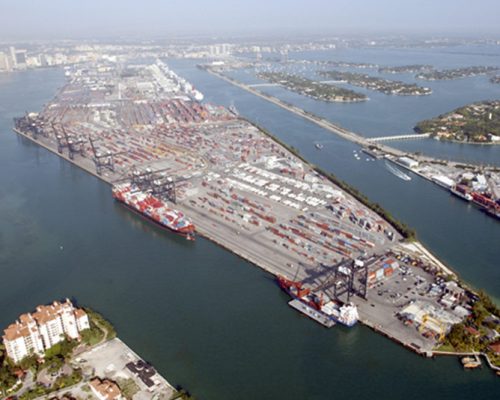 Arial photo of the Port of Miami with large number of cargo containers, container ship and barge.