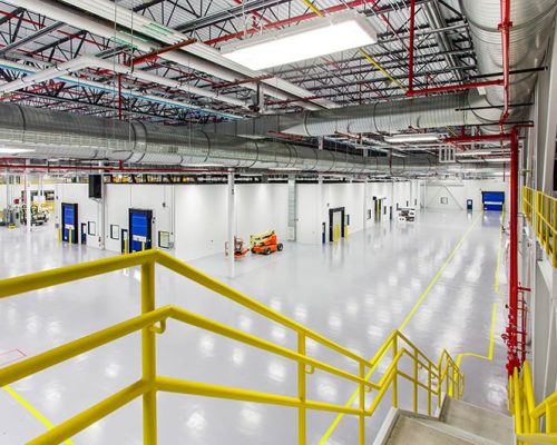 Interior of SAFRAN Aerospace Composite Facility. Large open white room with bright lights and yellow railing.