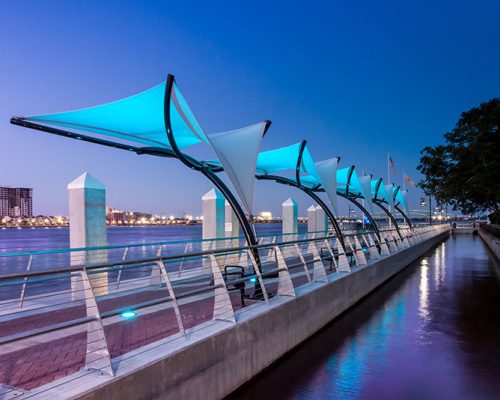 Photo of Jacksonville's Southbank Riverwalk at dusk. Blue LED lights illuminate the canopies.
