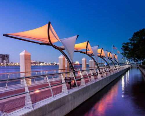 Photo of Jacksonville's Southbank Riverwalk at dusk. LED lights change colors and illuminate the canopies.