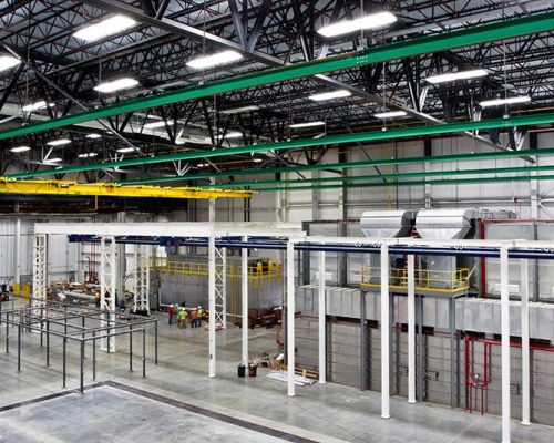 Interior of Spirit AeroSystems Composite Center. Large industrial room with green, yellow and white rafters.