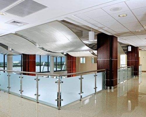 Interior photo from inside St John Broken Arrow. Wave like structures hang form the ceiling. Frosted glass and metal railing surround the overlook.