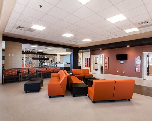 Waiting area inside the TMC Rincon Health Campus. Orange chairs and brown tables sit in the middle of the room.